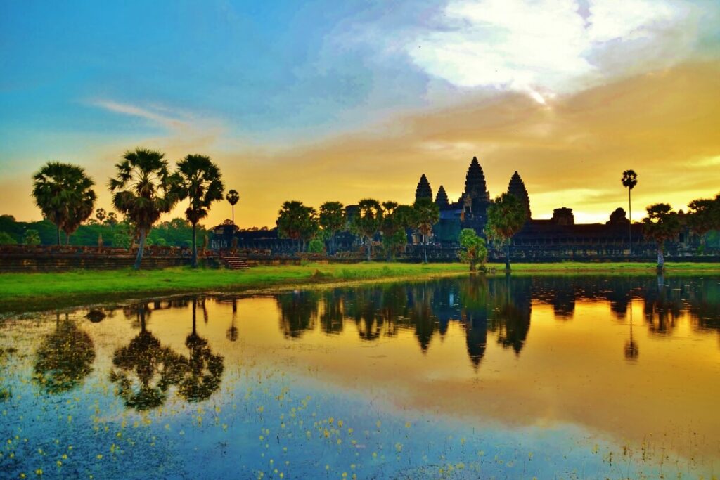 Sunset over Angkor Wat, Cambodia, illuminating the ancient temple complex with warm hues of orange and pink.