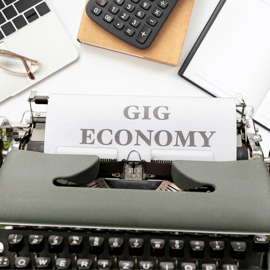 Various tools used in side gigs or side hustles, including a typewriter, laptop, and notebook, representing flexible work opportunities.