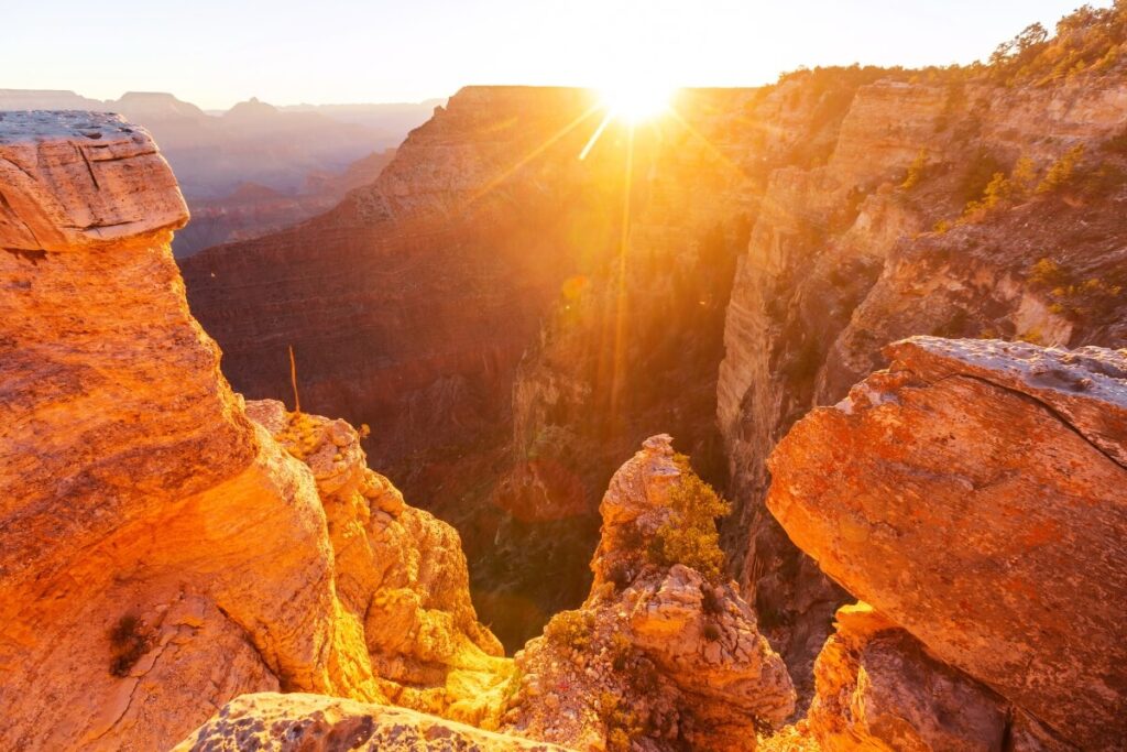 Sunset over the Grand Canyon in the USA, with vibrant hues of orange, pink, and purple illuminating the canyon's rugged landscape.