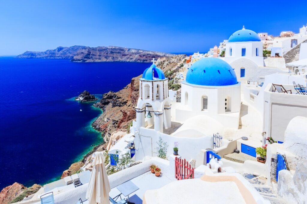 A scenic view of Santorini, Greece, featuring iconic white buildings with blue domes overlooking the Aegean Sea.