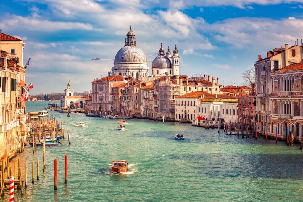 Scenic view of Venice, Italy, showcasing its iconic canals, gondolas, and historic buildings under a clear blue sky.