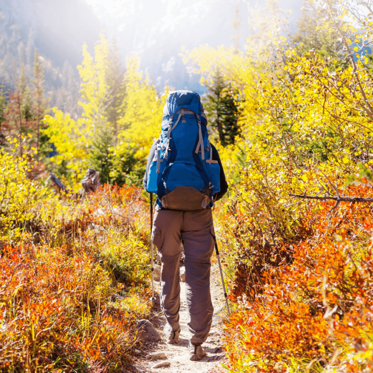 Hiker with a backpack standing on a cliff's edge overlooking a scenic valley, symbolizing budget-friendly adventure.